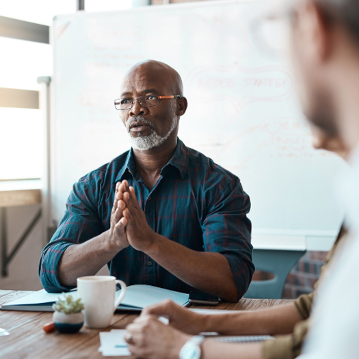 A black male social worker (or other professional) addressing a meeting around a table