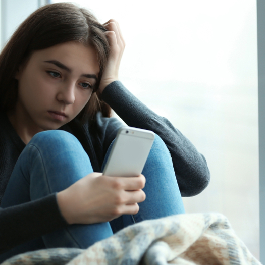 A young girl looking down or shamed while looking at her phone